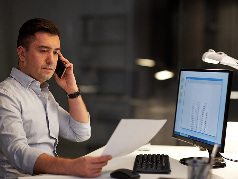 man on phone working on computer